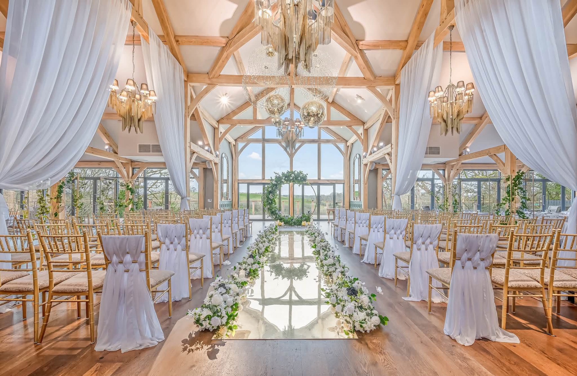 The ceremony room at Enterkine House with wooden beams, chandeliers and a flower-lined aisle